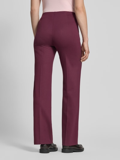 Frauenmodel trägt Hose aus Viskose-Mix mit Reißverschlusstaschen von Marc Cain in Dunkelrot, Regular-Fit, Bügelfalten, Ganzkörperansicht Rückansicht.