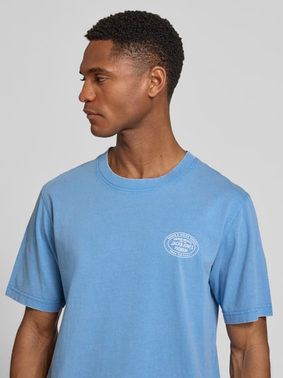 Männermodel trägt T-Shirt mit Label-Print Modell 'FELIX' van Jack & Jones Premium in lichtblauw, katoen, regular fit, ronde hals, detailopname bovenlichaam.