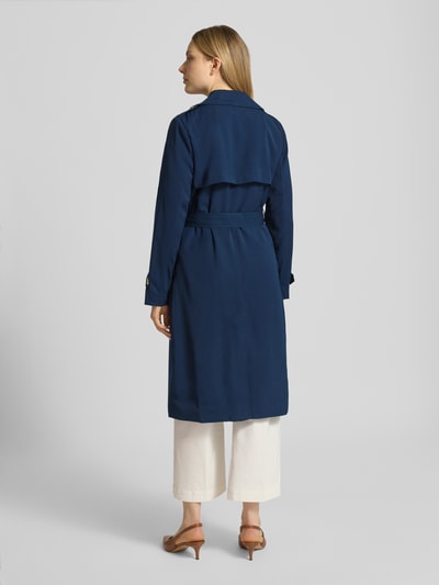 Vrouwenmodel draagt Zweireihiger Trenchcoat mit Bindegürtel van MICHAEL Michael Kors in regular fit, donkerblauw, met reverskraag, strikceintuur, ruglengte maat S 47 cm, schouderbreedte 40 cm, borstwijdte 50 cm, mouwlengte 63 cm, geheel zichtbaar van achteren.