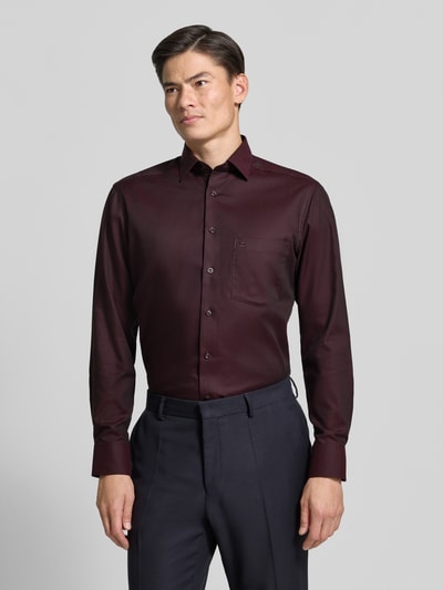 Männermodel trägt Comfort Fit Businesshemd aus reiner Baumwolle von OLYMP Luxor in Dunkelrot, glatte Textur, Ganzkörperansicht von vorne.