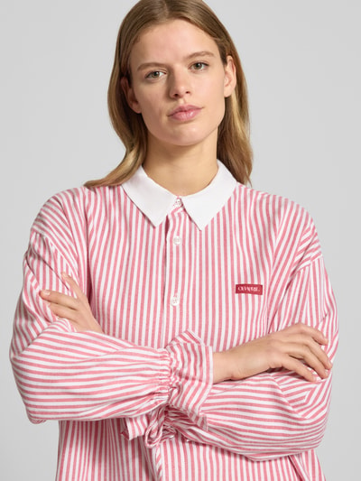 Frauenmodel trägt Hemdbluse mit Label-Detail von OH APRIL in Rosa-Weiß mit Streifen, Baumwoll-Viskose-Mix, Knopfleiste, Nahaufnahme Oberkörper.