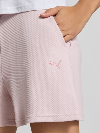 Frauenmodel trägt Loose Fit Sweatshorts aus Baumwoll-Mix Modell 'ESS ELEVATED' von PUMA in Hellrosa mit feiner Rippstruktur, Nahaufnahme Oberschenkel. Damen Sweatshorts von PUMA.