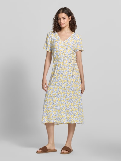 Frauenmodel trägt A-Linien Midikleid aus reiner Viskose Modell 'BARRI' von Pieces, Optik:Allover-Muster, Midi-Länge, Rundhals, Knopf-Verschluss, Ärmelform: Ohne, Saum: Gerade, Material: Reine Viskose, florale Muster in Gelb und Blau, glatte Textur, Ganzkörperansicht von vorne.