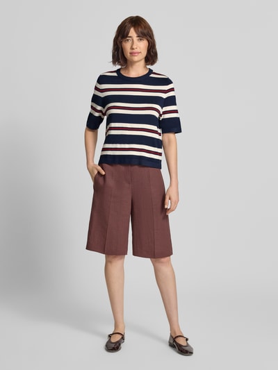 Frauenmodel trägt Boxy Fit Strickshirt aus Viskose-Mix Modell 'VMSILJE' von VERO MODA mit Streifen in Dunkelblau, Weiß und Rot, Ganzkörperansicht von vorne. Damen Strickshirt von VERO MODA.
