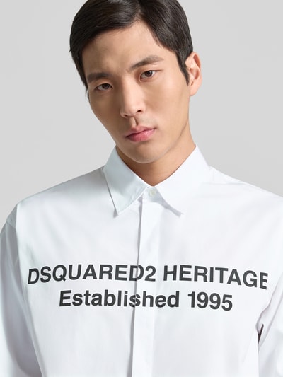 Männermodel trägt Regular Fit Freizeithemd aus Baumwolle von Dsquared2 in Weiß mit schwarzem Schriftzug, Nahaufnahme Oberkörper.