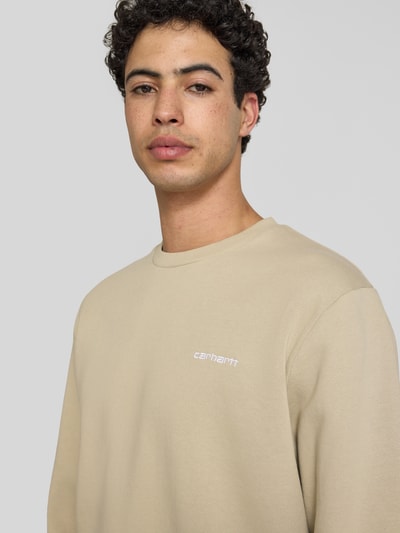 Männermodel trägt Sweatshirt mit Rundhalsausschnitt und Label-Stitching von Carhartt Work In Progress, Baumwoll-Elasthan-Mix, Regular-Fit, Nahaufnahme Oberkörper.