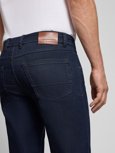 Männermodel trägt Straight Fit Jeans aus Baumwoll-Mix von bugatti, ciemnoniebieski kolor, 5 kieszeni, zapięcie na guzik i zamek błyskawiczny, mieszanka bawełny, widoczna metka z logo, Szerokość w rozmiarze 32/32: 43 cm, Długość wewnętrzna nogawki: 80 cm, detal z tyłu, Ganzkörperansicht Rückansicht.