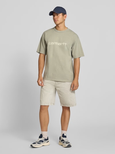 Męski model nosi Regular Fit T-Shirt aus reiner Baumwolle Model 'Painter' von Carhartt Work In Progress, kolor jasnoszary, detal z logo, Długość tyłu w rozmiarze M: 72 cm, Ganzkörperansicht von vorne