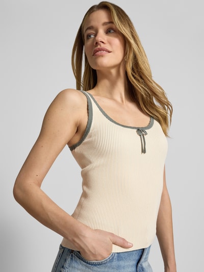 Frauenmodel trägt Slim Fit Tank Top aus Viskose-Mix Modell 'Bardot' von Vero Moda in Optik: Unifarben, Rippstrick, U-Ausschnitt, breite Träger, Materialverarbeitung: Viskose-Mix, helle Farbe mit kontrastfarbener Umrandung, Nahaufnahme Oberkörper.