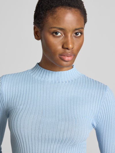 Frauenmodel trägt hellblauen Slim Fit Pullover aus reiner Baumwolle Modell 'ALAANIA' von ARMEDANGELS, gerippte Textur, Nahaufnahme Oberkörper.