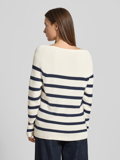 Frauenmodel trägt Regular Fit Strickpullover aus reiner Baumwolle von Tommy Hilfiger in Optik: Allover-Muster, Gestreift, Logo-Stitching, V-Ausschnitt, Langarm, Raglanärmel, Materialverarbeitung: Rippstrick, in Creme mit dunkelblauen Streifen, angenehme Baumwollstruktur, Ganzkörperansicht Rückansicht.