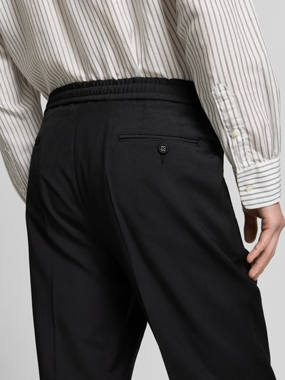 Männermodel trägt Straight Fit Stoffhose aus reiner Wolle von Officine Générale, Bügelfalte, Gesäßtaschen, Nahaufnahme Rückansicht.
