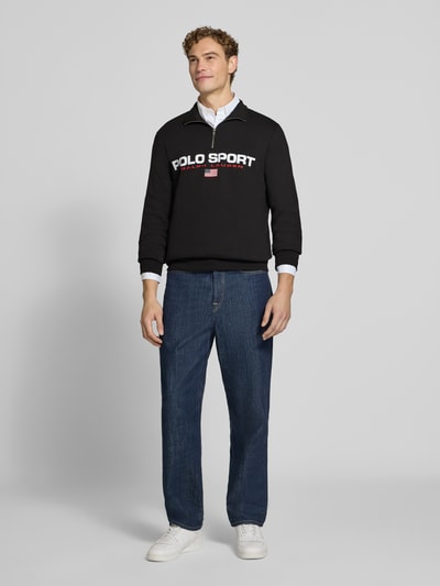 Męski model nosi Relaxed Fit Troyer aus Baumwoll-Mix od Polo Ralph Lauren, czarny ze sportowym nadrukiem, znacznie fakturowana tkanina, Ganzkörperansicht von vorne.