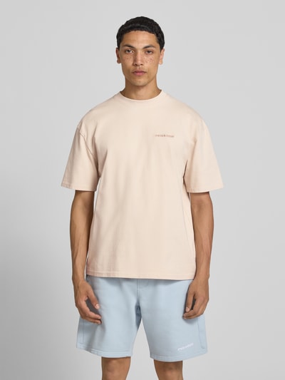 Männermodel trägt Oversized T-Shirt mit Label-Stitching von Pegador aus Baumwoll-Mix, Rundhalsausschnitt, beige, Ganzkörperansicht von vorne. Rückenlänge bei Größe M: 70 cm.