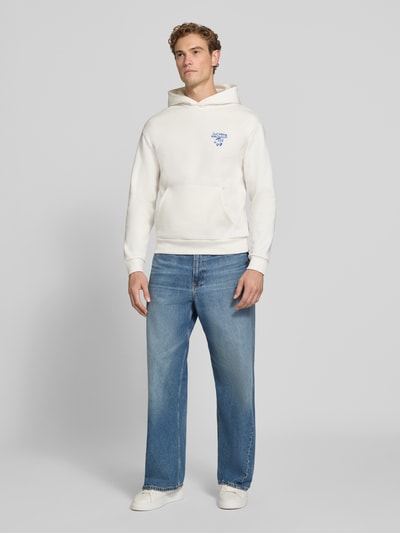 Männermodel trägt Relaxed Fit Hoodie mit Motiv-Print von REVIEW, Baumwoll-Mix, gerippte Abschlüsse, jeans, Ganzkörperansicht von vorne.