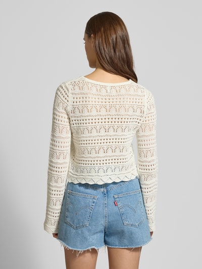 Frauenmodel trägt Cropped Strickpullover aus Baumwoll-Mix Modell 'ELKE' von ONLY, Unifarben, Boxy-Fit, Lochstrickmuster, Rundhals, Langarm, Materialverarbeitung Lochstrick, Material Baumwoll-Mix, Ganzkörperansicht Rückansicht.