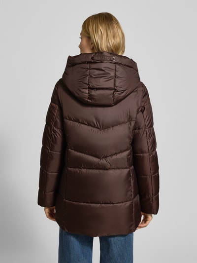 Frauenmodel trägt Regular Fit Steppjacke mit Kapuze von s.Oliver CASUAL in Braun, Stehkragen, unifarben, leicht abgerundet, Ganzkörperansicht Rückansicht.