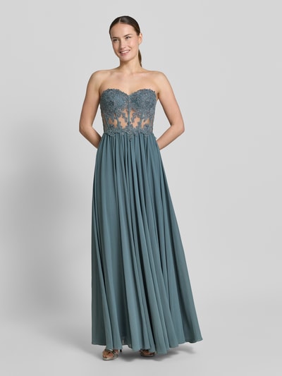 Frauenmodel trägt Abendkleid mit Spitze und Gehschlitz von Mascara in Blau, Herz-Ausschnitt, Strassbesatz, semitransparent, tailliert, Ganzkörperansicht von vorne.