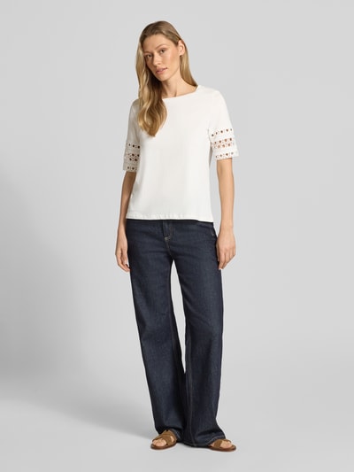 Frauenmodel trägt Regular Fit T-Shirt aus reiner Baumwolle Modell 'IVACY' von Vero Moda, weiß, Lochstickerei-Besatz, Ganzkörperansicht von vorne.