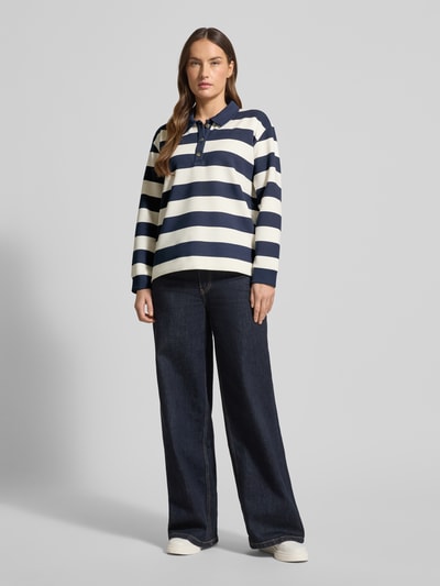 Frauenmodel trägt Sweatshirt mit Polokragen und Knopfleiste von Christian Berg Woman im Material-Mix mit Modal-Anteil, Regular-Fit, blaue und weiße Blockstreifen, lockere Struktur, Ganzkörperansicht von vorne.