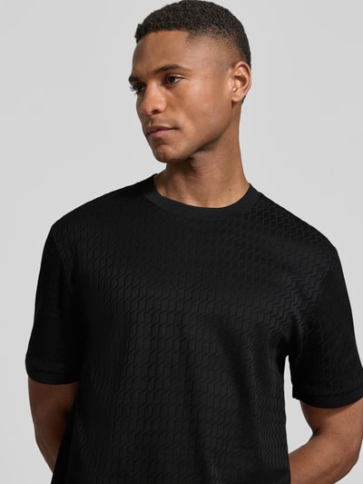 Männermodel trägt Regular Fit T-Shirt aus reiner Baumwolle Modell 'THOMSON' von BOSS, schwarz, feines Strukturmuster, Nahaufnahme Oberkörper