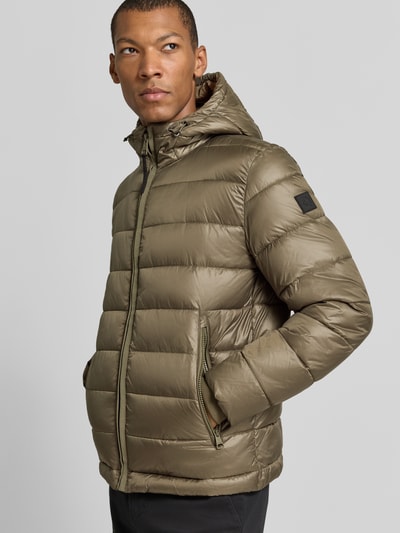 Męski model nosi Regular Fit Steppjacke mit Storm Cuffs Modell 'BAVENO' od Strellson, kolor jednolity, połyskujący, kaptur, zamek kryty, długie rękawy z mankietami Storm Cuffs, tkanina pikowana, zapewnia izolację cieplną, kieszenie zapinane na zamek, wewnętrzna kieszeń na rzep, krój regular fit, widok całopostaciowy z przodu.