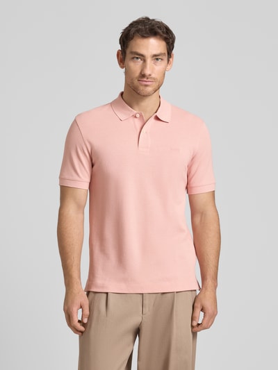 Männermodel trägt Regular Fit Poloshirt aus reiner Baumwolle Modell 'PALLAS' von BOSS in Optik: Unifarben, Ganzkörperansicht von vorne. Applikation: Label-Stitching-Applikation, Kragenform: Polokragen, Verschluss: 2-Knopf-Verschluss, Ärmelform: Kurzarm, Materialverarbeitung: Piqué.
