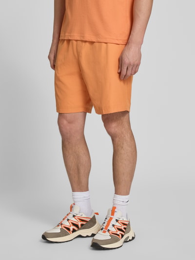 Mannelijk model draagt Relaxed Fit Sport-Shorts met Logo-Stitching van Lacoste Sport, effen oranje, elastische tailleband, zijzakken, tunnelkoord, relaxed fit. Detailopname benen.