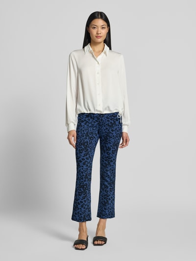 Frauenmodel trägt Flared Fit Leggings mit Allover-Animal-Print von Marc Cain, elastischer Material-Mix, Bund und Logo-Detail, Ganzkörperansicht von vorne.
