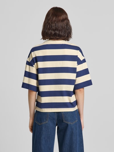 Frauenmodel trägt Oversized T-Shirt aus reiner Baumwolle von s.Oliver RED LABEL mit breiten blauen und beigen Streifen, Ganzkörperansicht Rückansicht.