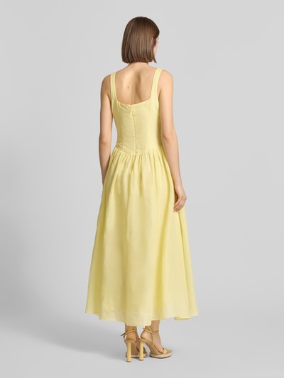 Frauenmodel trägt Midikleid aus Ramie Modell 'LAWRENCE SCOOP' von Bardot in Hellgelb, A-Linie, Karree-Ausschnitt, Rückenansicht, Rückseitiger Reißverschluss, Rückenlänge bei Größe 36: 114 cm, Brustweite: 43 cm, fließende Textur. Ganzkörperansicht Rückansicht.