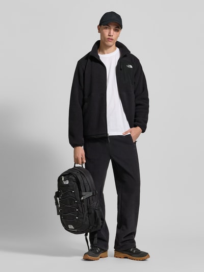 Męskamodel nosi kurtkę z polaru z napoleońską kieszenią model 'YUMIORI' od The North Face, polar, prosty krój, wpuszczane kieszenie, elastyczne wykończenia, długość tyłu 70 cm, długość rękawów 70 cm, czarna, gładka faktura, całkowity widok z przodu.