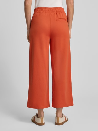 Vrouwenmodel draagt Wide Fit Stoffhose met Viskose-Anteil Modell 'Kate' van ICHI in oranje, elastische taille, rechte pijpen, Ganzkörperansicht Rückansicht.