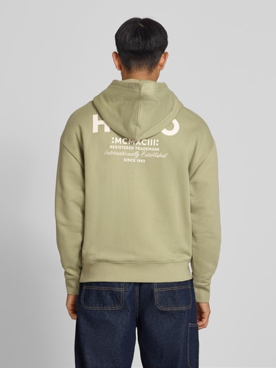 Männermodel trägt Loose Fit Hoodie aus reine katoen model 'Nazardo' van HUGO in lichtgroen met witte tekstprint, Heren Hoodie von HUGO Blue, Ganzkörperansicht Rückansicht