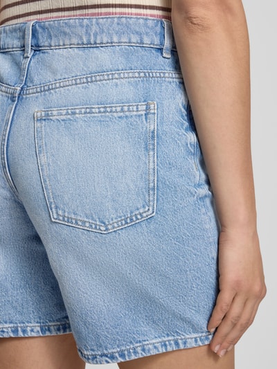 Vrouwenmodel draagt Jeansshort in middelblauwe wassing van REVIEW, puur katoen, regular fit, steekzakken, detailopname achterkant