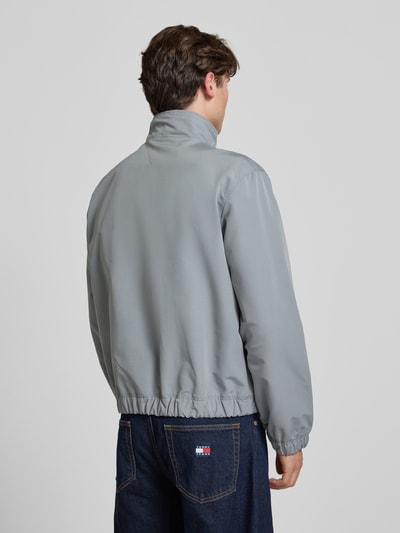 Männermodel trägt Regular Fit Bomberjacke mit Label Stitching von Tommy Jeans in Optik: Unifarben, Ganzkörperansicht Rückansicht.