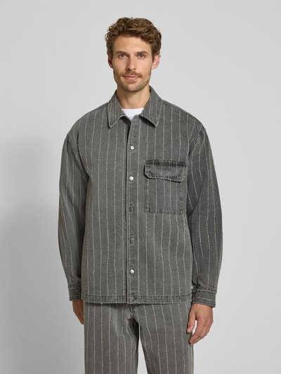 Männermodel trägt Regular Fit Hemdjacke aus reiner Baumwolle Modell 'David' von Wood Wood in grau mit Streifen und Brusttasche, Ganzkörperansicht von vorne.