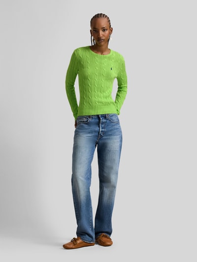 Frauenmodel trägt grünen Strickpullover mit Zopfmuster Modell 'JULIANNA' von Polo Ralph Lauren aus Baumwolle, Slim Fit, Ganzkörperansicht von vorne.