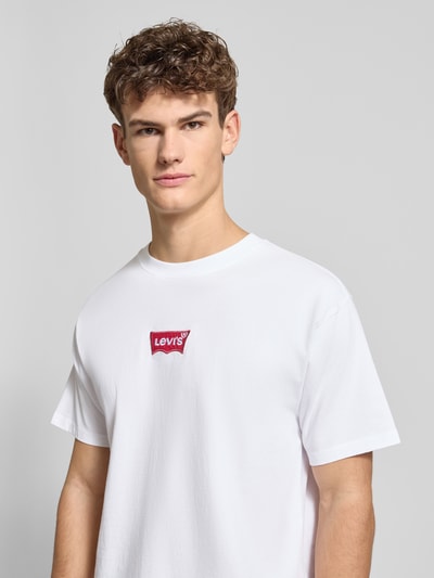 Männermodel trägt T-Shirt mit Label-Detail von Levi's®, weiße Baumwolle, lockerer Schnitt, gerippter Rundhalsausschnitt, Nahaufnahme Oberkörper.