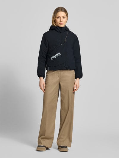 Vrouwenmodel draagt zwarte jack met capuchon en labeldetail, regular fit, model 'SHELLY2' van khujo, volledig van voren.