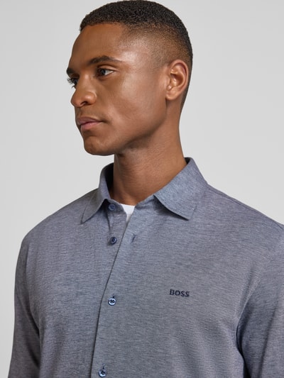 Mężczyzna nosi Slim Fit koszulę casualową z czystej bawełny Model 'MYSOFT_2' od BOSS Orange, efekt: jednolity kolor, melanż, haftowane logo, kołnierzyk typu kent, listwa guzikowa jednorzędowa, długi rękaw, sportowe mankiety, zaokrąglone wykończenie, materiał: bawełna, efekt melanżowy. Ujęcie: zbliżenie na górną część ciała.