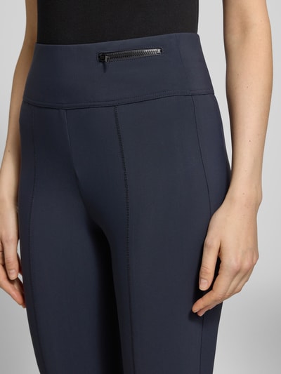 Frauenmodel trägt Loose Fit Jogpants mit breitem Bund von Marc Cain, Elastischer-Material-Mix, Teilungsnähte, Reißverschlusstasche, Nahaufnahme Oberkörper.