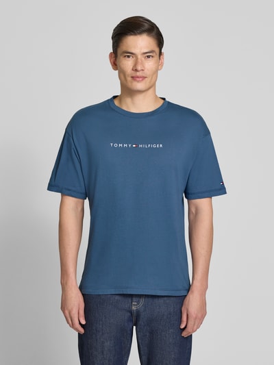 Männermodel trägt Regular Fit T-Shirt mit Label-Schriftzug aus reiner Baumwolle von Tommy Hilfiger, unifarben, Ganzkörperansicht von vorne.
