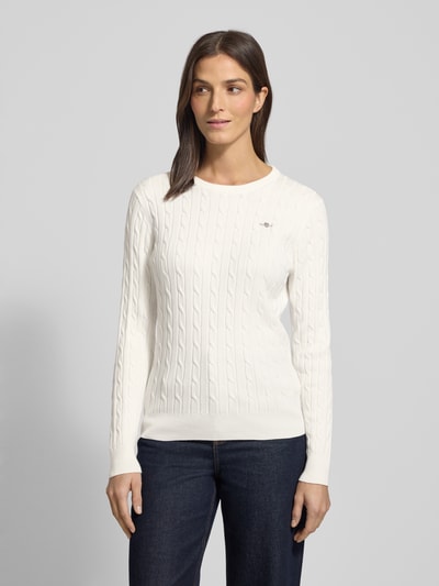 Vrouwenmodel draagt Strickpullover met Label-Detail van GANT, wit, structuurpatroon, ronde hals, geribde afwerking, close-up bovenlichaam.