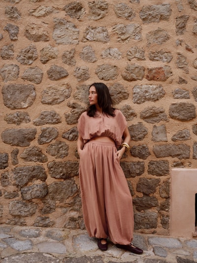 Frauenmodel trägt Cropped Blusentop mit Knopfverschluss curated by Anna Schürrle von Style Icon Collection in Beige mit elastischem Bund und Rundhalsausschnitt, Damen Blusentop; Ganzkörperansicht von vorne.