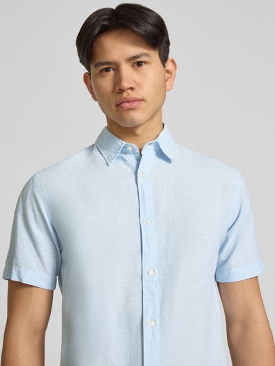 Męski model nosi Regular Fit Freizeithemd aus Baumwoll-Leinen-Mix od Jack & Jones, jasnoniebieski kolor, model BREEZE, kołnierzyk typu kent, listwa guzikowa, mieszanka bawełny i lnu, krój regular fit, koszula casualowa, długość tyłu w rozmiarze M: 76 cm, szerokość w rozmiarze M: 50 cm, długość rękawów w rozmiarze M: 26 cm, zbliżenie na górną część ciała