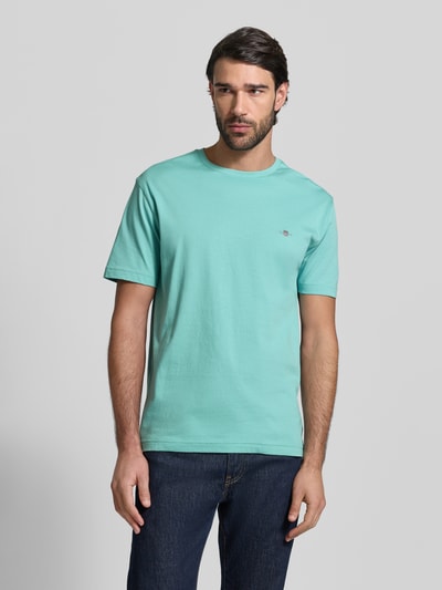 Męski model nosi Regular Fit T-Shirt mit Logo-Stitching od Gant, czysta bawełna, krój regular fit, dekolt okrągły, widok całej sylwetki z przodu.
