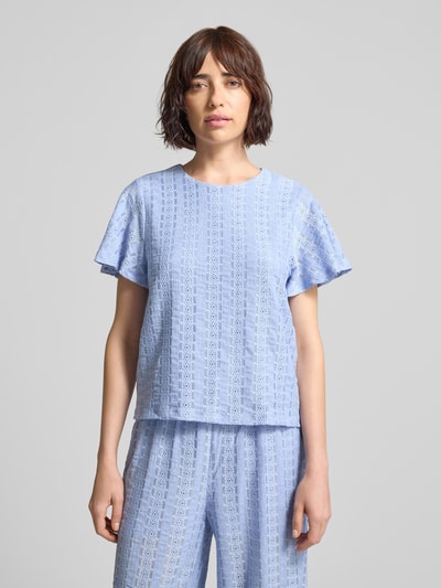 Kobiece model prezentuje bluzkę z krótkim rękawem z haftem angielskim model 'CASSANDRA' od Vero Moda, efekt: jednolity kolor, krój regular fit, okrągły dekolt, wykończenie materiału: haft angielski, jasnoniebieska, zdjęcie: całkowity widok od przodu.