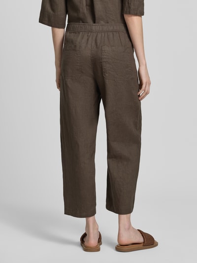 Frauenmodel trägt Leinenhose in verkürzter Passform Modell 'myha linen' von OPUS in Braun mit elastischem Bund, reine Leinen, Ganzkörperansicht Rückansicht. Bundweite bei Größe 36: 41 cm, Innenbeinlänge bei Größe 36: 65 cm.