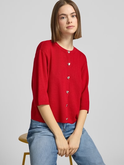 Frauenmodel trägt Regular Fit Strickjacke aus Viskose-Mix Modell 'MAISIE' von Only in Rot mit Schmuckknöpfen, Feinstrick, Nahaufnahme Oberkörper.